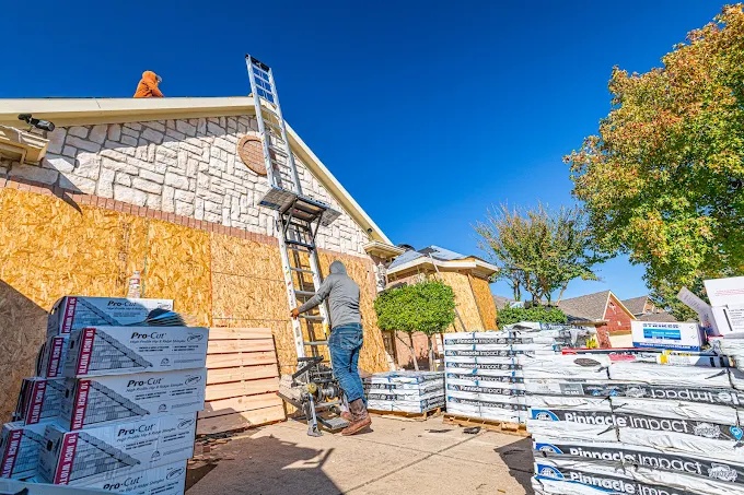 Roofing crew delivering shingles and underlayment to a job site